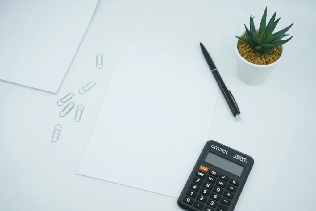 Calculator and pen arranged on a clean office desk.