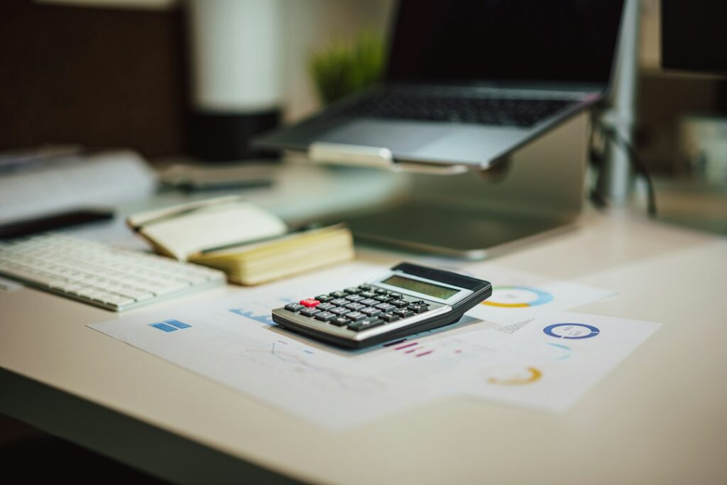 Calculator, notebook, and financial paperwork on a desk.
