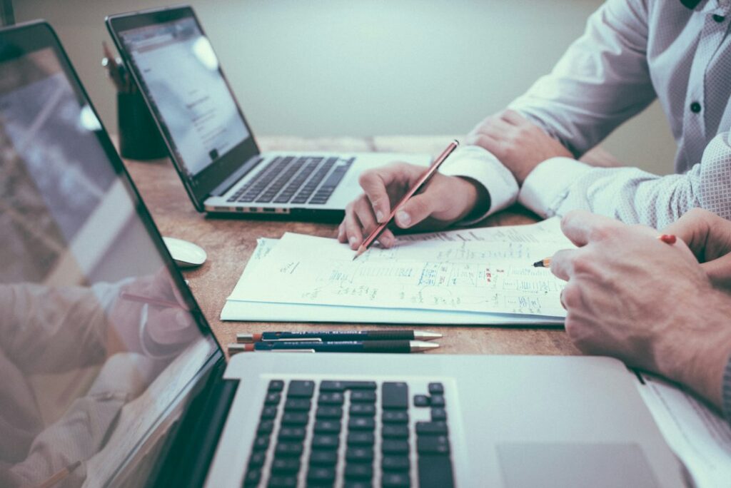 Financial paperwork being reviewed beside a laptop.